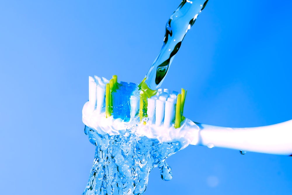 Tandbørste under rindende vand